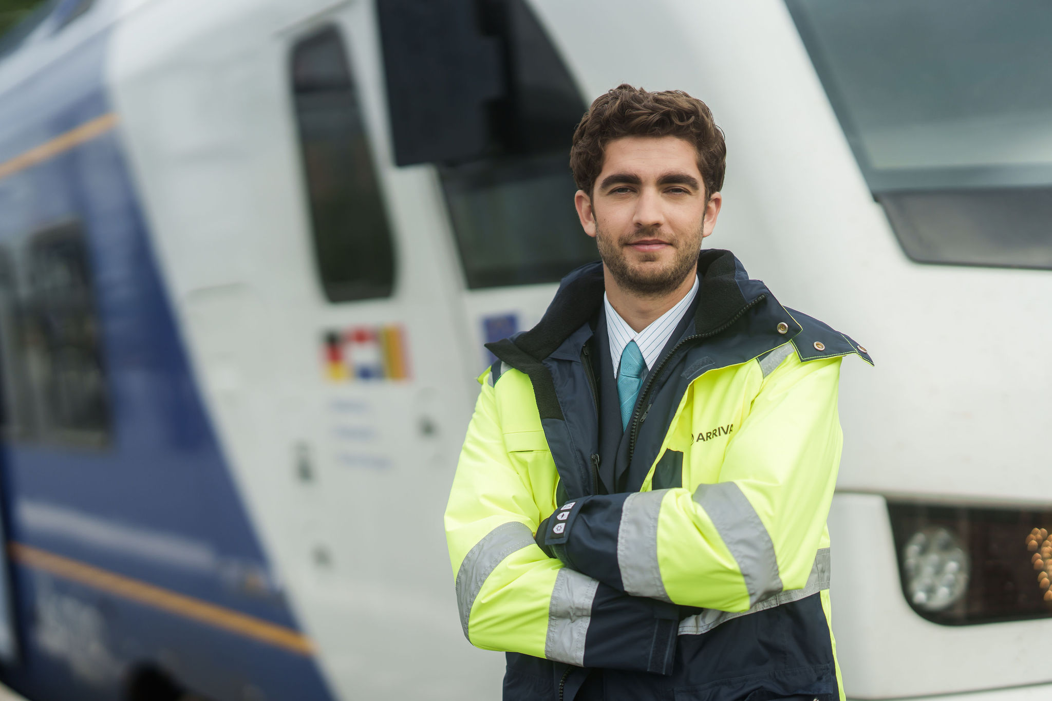 Machnist van Arriva staat met de armen over elkaar voor een trein.