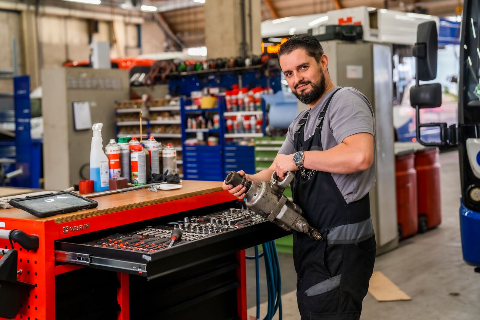 Monteur van Arriva in werkplaats met luchtsleutel in de hand, staand voor een werkbank.