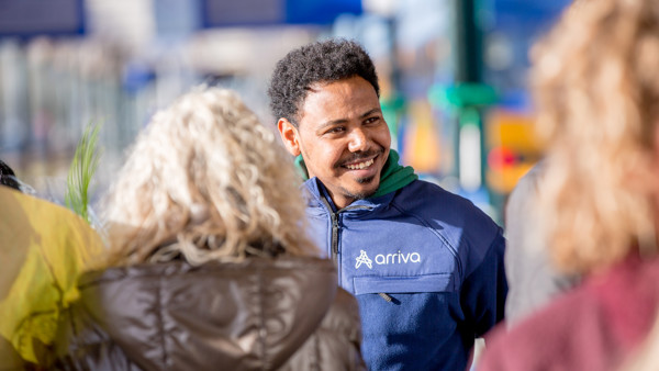 Een vrolijke man in een blauw Arriva uniform lacht naar mensen, de zon schijnt. Een vrolijke man in een blauw Arriva uniform lacht naar mensen, de zon schijnt.