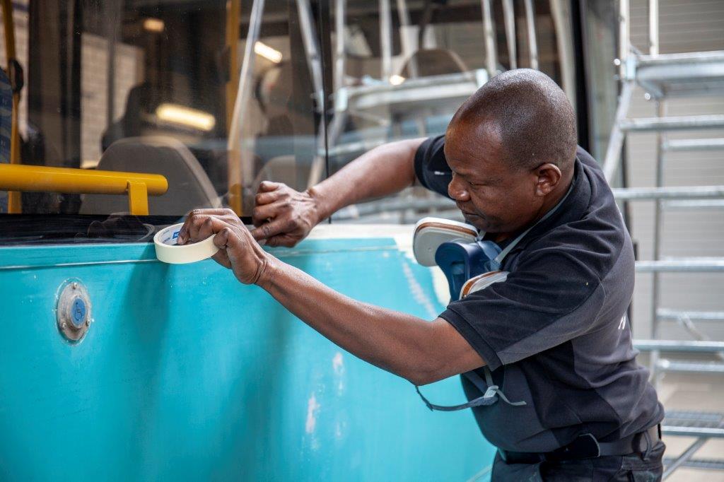 Monteur plakt bus blauwe Arriva-bus af met verftape 