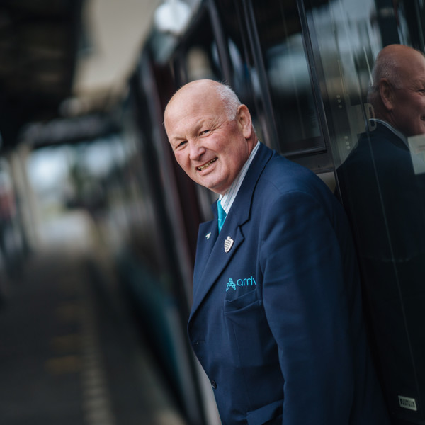 Steward Gerrie Drent staat lachend tegen een Arriva-trein geleund. Steward Gerrie Drent staat lachend tegen een Arriva-trein geleund.