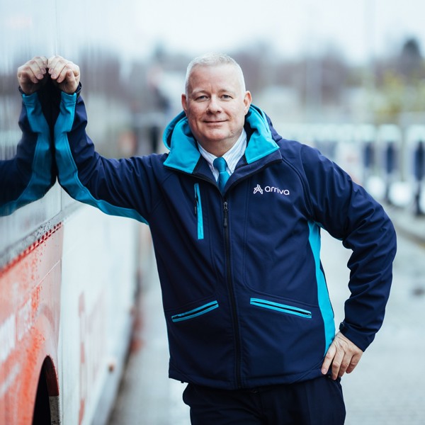 Buschauffeur Ron leunt relaxed en lachend tegen zijn Arriva-bus. Buschauffeur Ron leunt relaxed en lachend tegen zijn Arriva-bus.