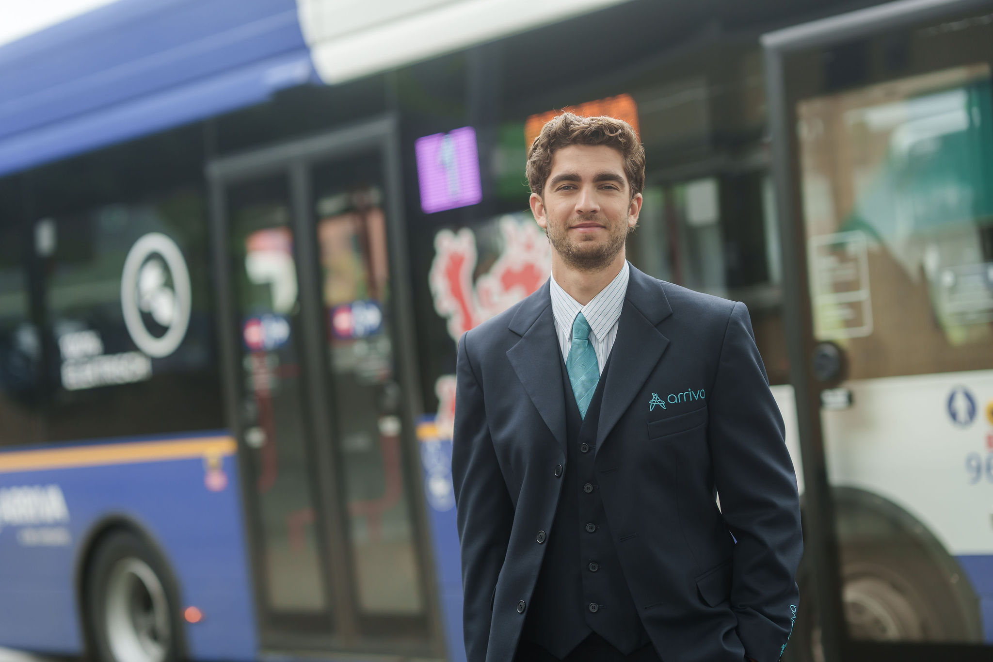 Een buschauffeur in Arriva-uniform staat voor een bus, met lijnnummer 1 en Arriva duidelijk zichtbaar op de achtergrond.