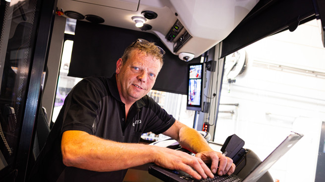 Monteur met de laptop op het stuur van de bus Monteur met de laptop op het stuur van de bus
