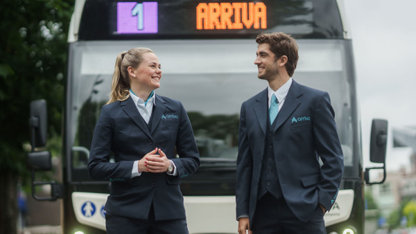 Twee lachende Arriva-buschauffeurs in uniform staan voor een bus met lijnnummer 1 en Arriva op de achtergrond. Twee lachende Arriva-buschauffeurs in uniform staan voor een bus met lijnnummer 1 en Arriva op de achtergrond.