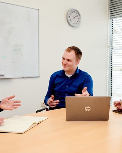 Vier jonge collega's van Arriva zitten aan een ronde tafel met laptops en vergaderen lachend met elkaar. Vier jonge collega's van Arriva zitten aan een ronde tafel met laptops en vergaderen lachend met elkaar.
