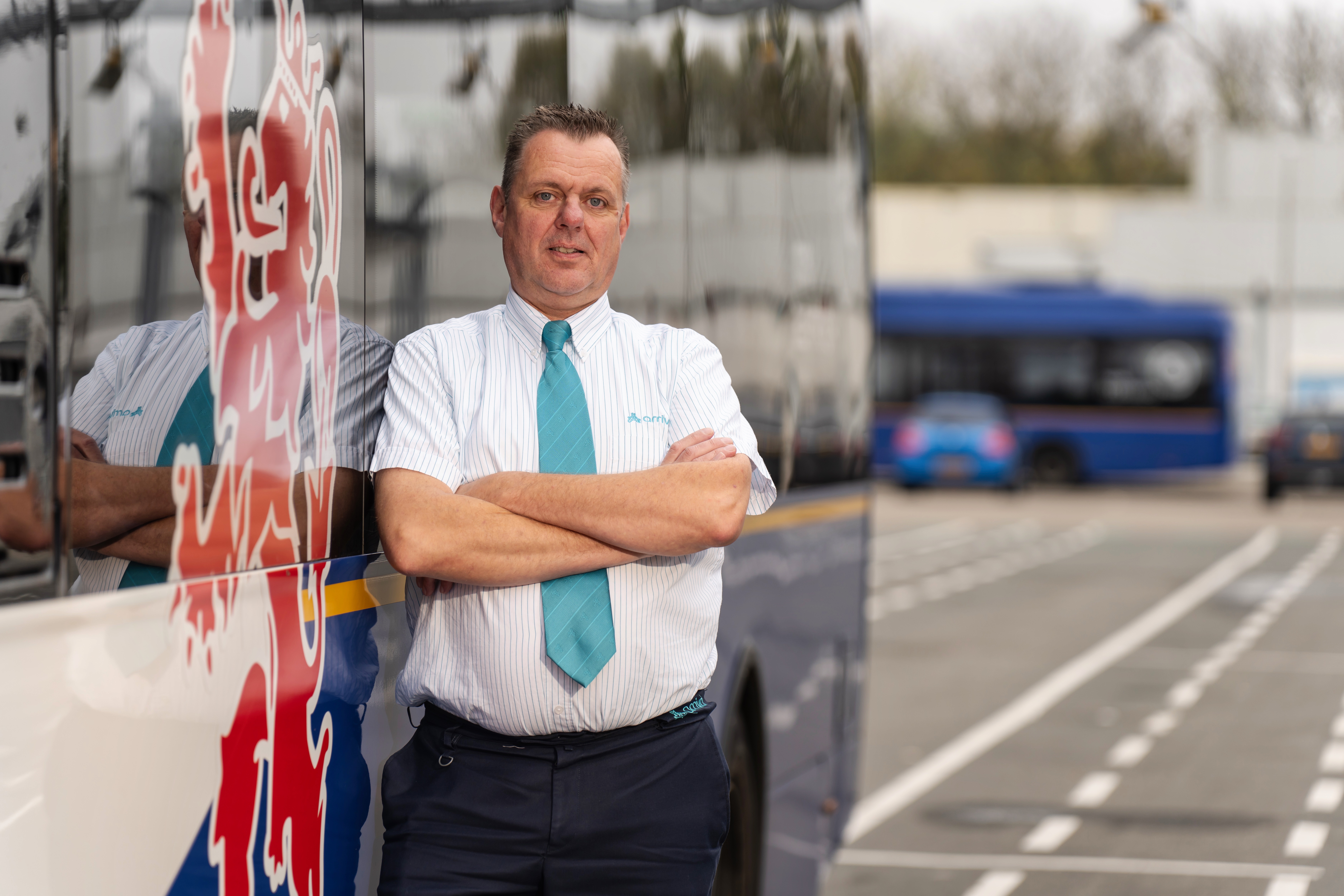 Buschauffeur van middelbare leeftijd staat voor een bus van Arriva 