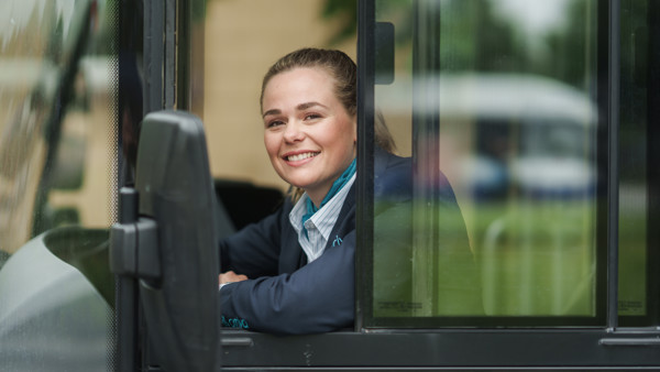 Arriva-chauffeur zit achter het stuur van haar bus en leunt relaxed uit haar zijraam en kijkt lachend in de camera. Arriva-chauffeur zit achter het stuur van haar bus en leunt relaxed uit haar zijraam en kijkt lachend in de camera.