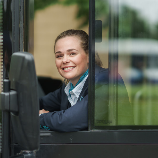 Arriva-chauffeur zit achter het stuur van haar bus en leunt relaxed uit haar zijraam en kijkt lachend in de camera. Arriva-chauffeur zit achter het stuur van haar bus en leunt relaxed uit haar zijraam en kijkt lachend in de camera.