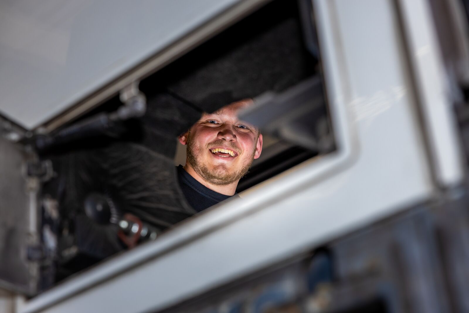 Monteur werkt in een Arriva-bus en kijkt lachend richting de camera.