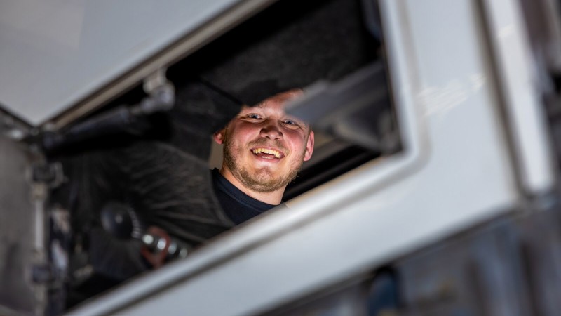 Monteur werkt in een Arriva-bus en kijkt lachend richting de camera. Monteur werkt in een Arriva-bus en kijkt lachend richting de camera.