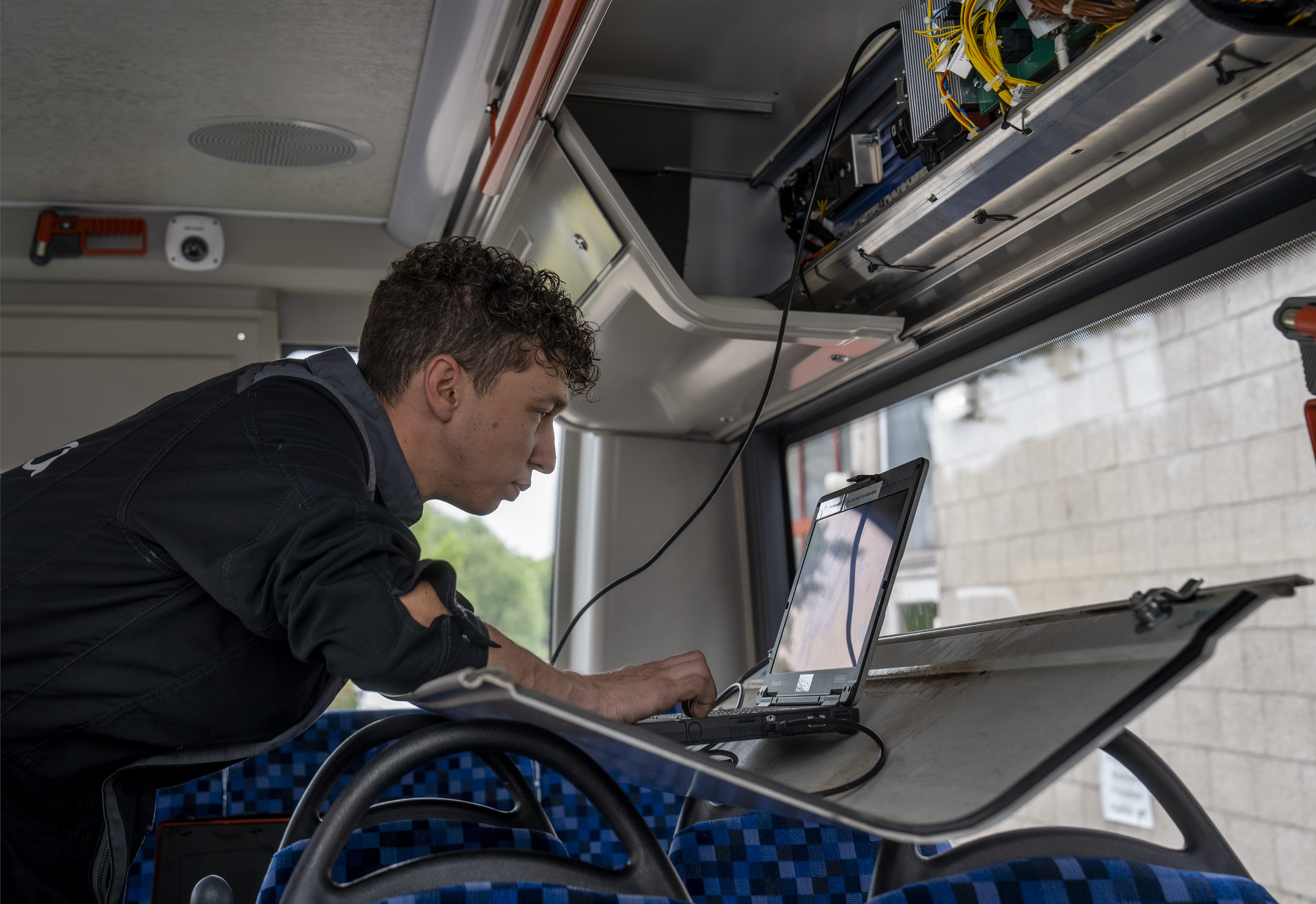 Monteur aan het werk in een Arriva bus, met behulp van een laptop.