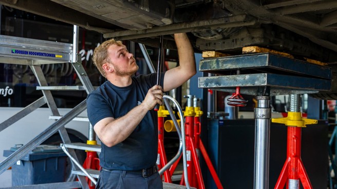 Monteur sleutelt aan onderkant Arriva-bus. Monteur sleutelt aan onderkant Arriva-bus.