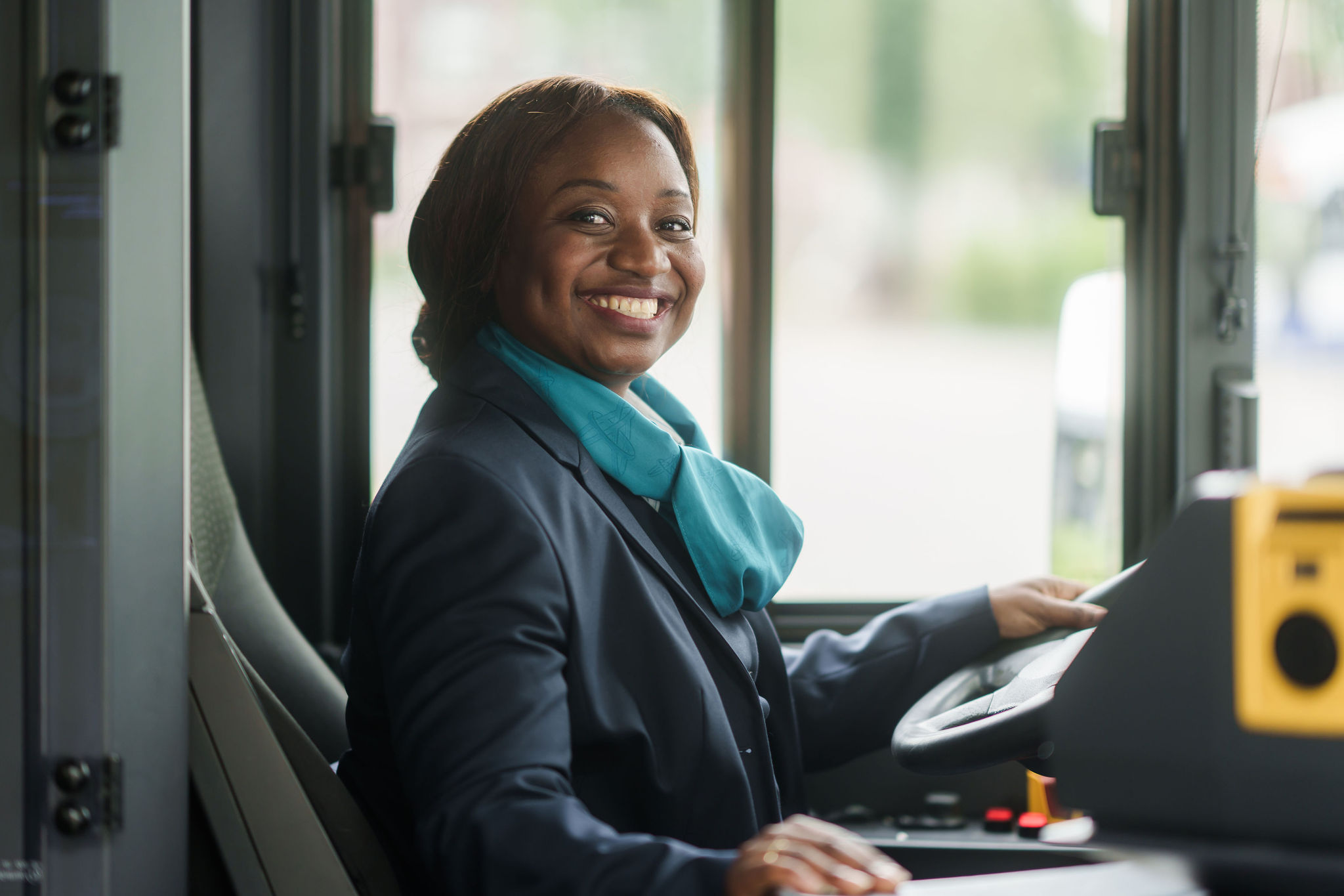Buschauffeur in haar Arriva-uniform kijkt lachend richting de ingang van haar bus