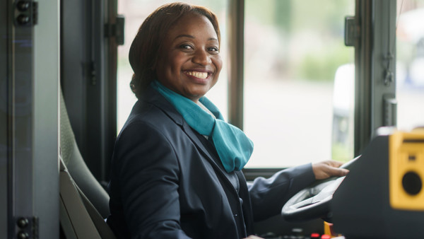 Buschauffeur in haar Arriva-uniform kijkt lachend richting de ingang van haar bus Buschauffeur in haar Arriva-uniform kijkt lachend richting de ingang van haar bus