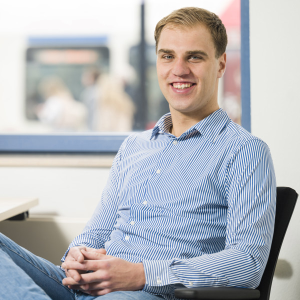 Glimlachende man zit in nonchalante houding achter een bureau Glimlachende man zit in nonchalante houding achter een bureau