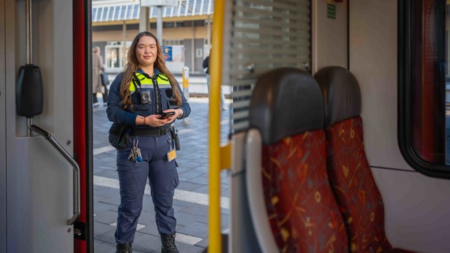 Jonge vrouw staat zelfverzekerd in de deuropening van een Arriva-trein Jonge vrouw staat zelfverzekerd in de deuropening van een Arriva-trein