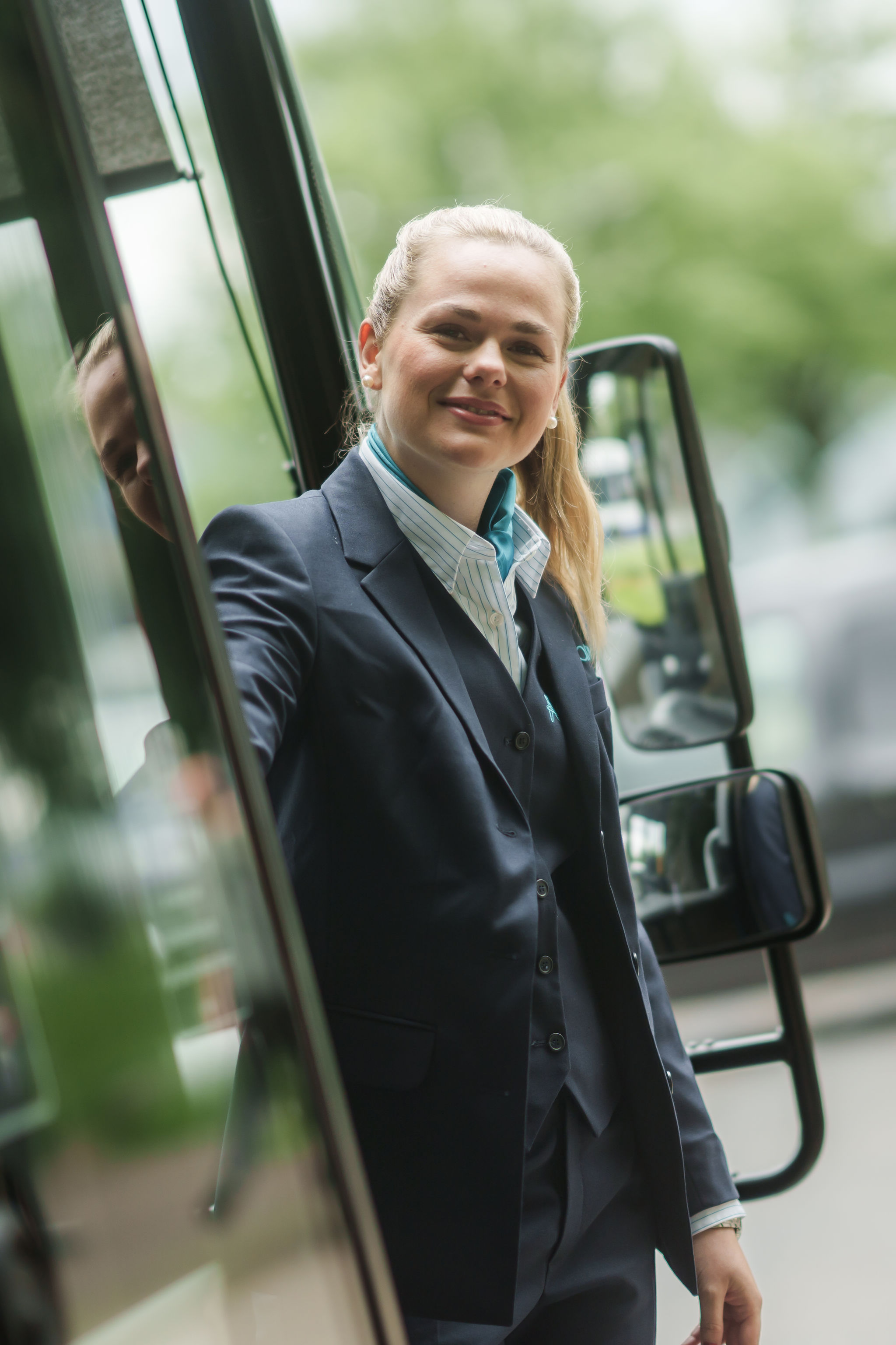 Buschauffeur hangt blij uit haar geparkeerde Arriva-bus.