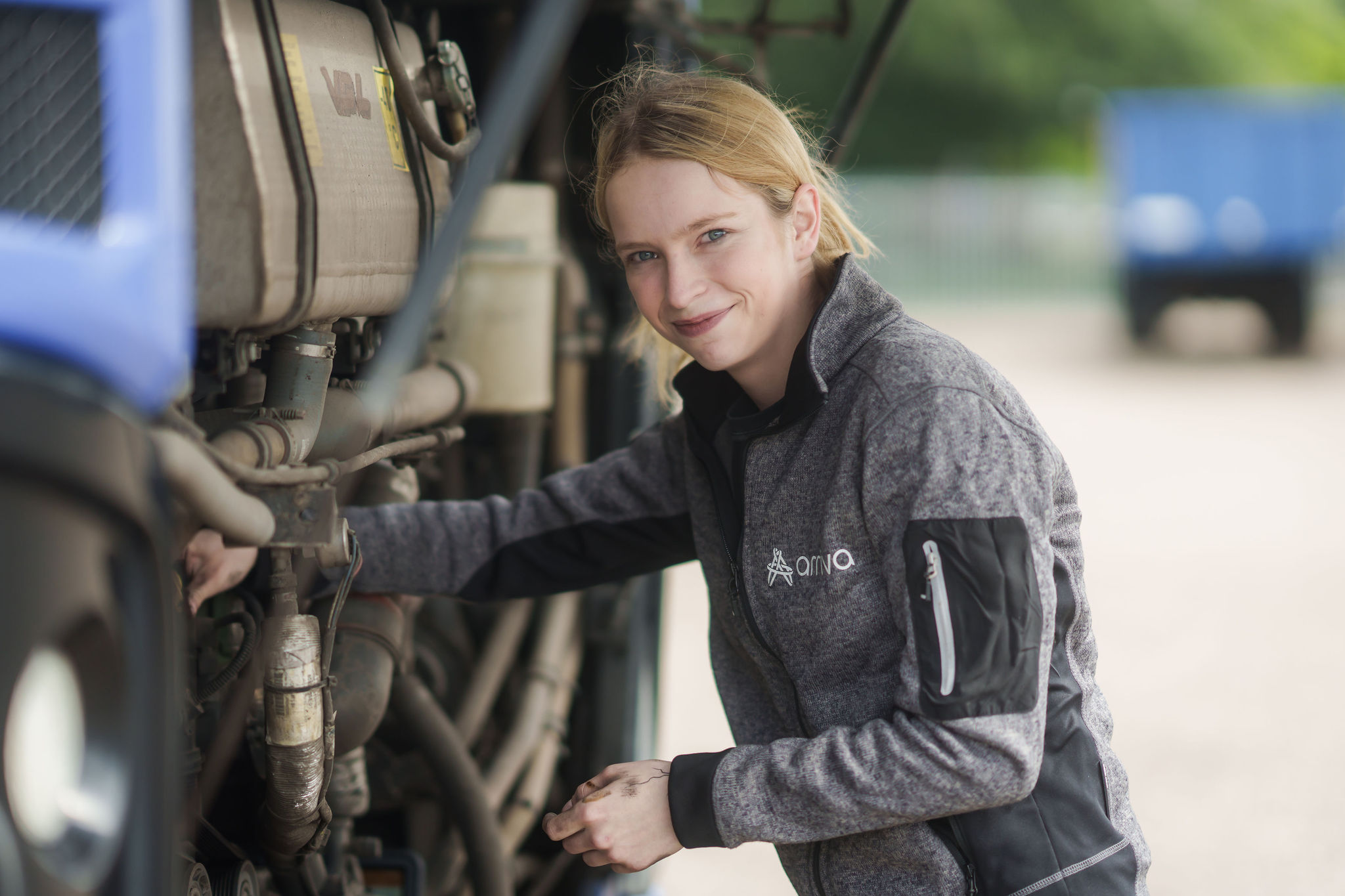 Jonge vrouw sleutelt aan een bus van Arriva en kijkt in de camera