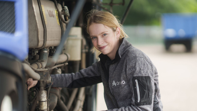 Jonge vrouw sleutelt aan een bus van Arriva en kijkt in de camera Jonge vrouw sleutelt aan een bus van Arriva en kijkt in de camera