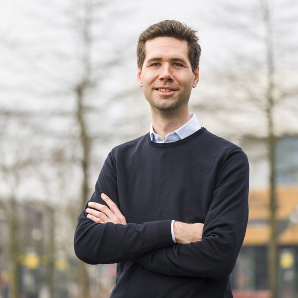 Glimlachende man staat buiten met zijn armen over elkaar Glimlachende man staat buiten met zijn armen over elkaar