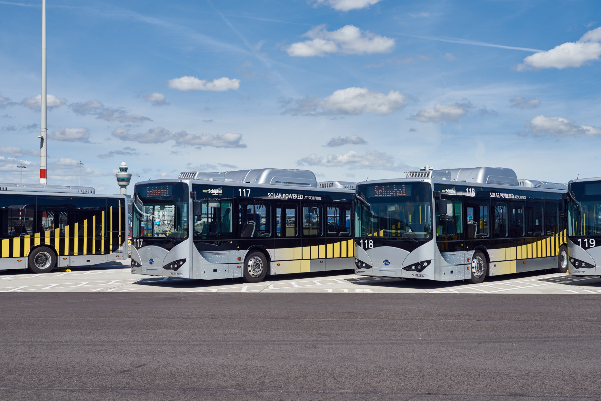 Elektrische zilver-gele Arriva-bussen op een rij onder een blauwe lucht met wolken.