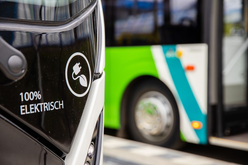 Arriva-bus met logo voor 100% elektrisch rijden. op de achtergrond staat nog een wit-groene Arriva bus.