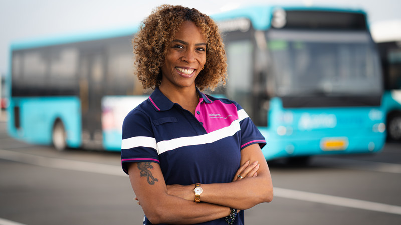 Chauffeur van Arriva in Schiphol-uniform staat met haar armen over elkaar en lacht naar de camera. Chauffeur van Arriva in Schiphol-uniform staat met haar armen over elkaar en lacht naar de camera.