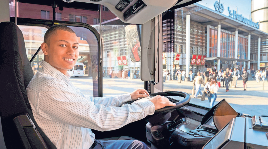 Studentchauffeur Tyrese glimlachend achter het stuur van de bus