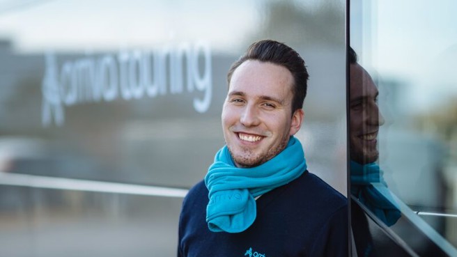 Touringcarchauffeur Benjaming staat lachend naast zijn touringcar. Touringcarchauffeur Benjaming staat lachend naast zijn touringcar.