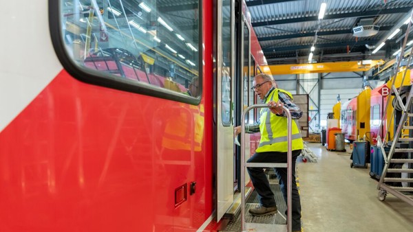 Rood-witte Arriva-trein in werkplaats, monteur in geel hesje stapt de trein in. Rood-witte Arriva-trein in werkplaats, monteur in geel hesje stapt de trein in.