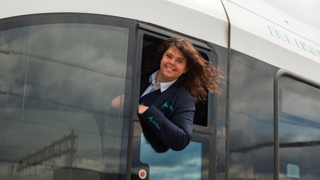 Machinist Gabriëlle Welmers hangt lachend uit het raam van haar cabine. Machinist Gabriëlle Welmers hangt lachend uit het raam van haar cabine.