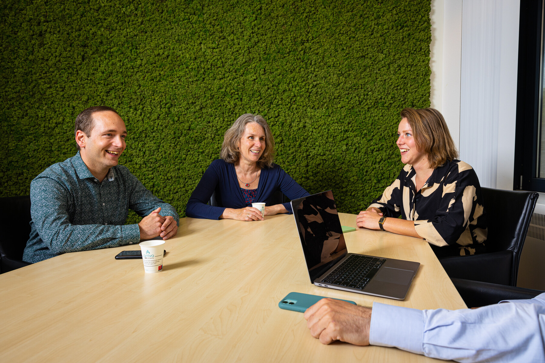 Vier medewerkers van Arriva zitten aan een bureau met elkaar te overleggen.