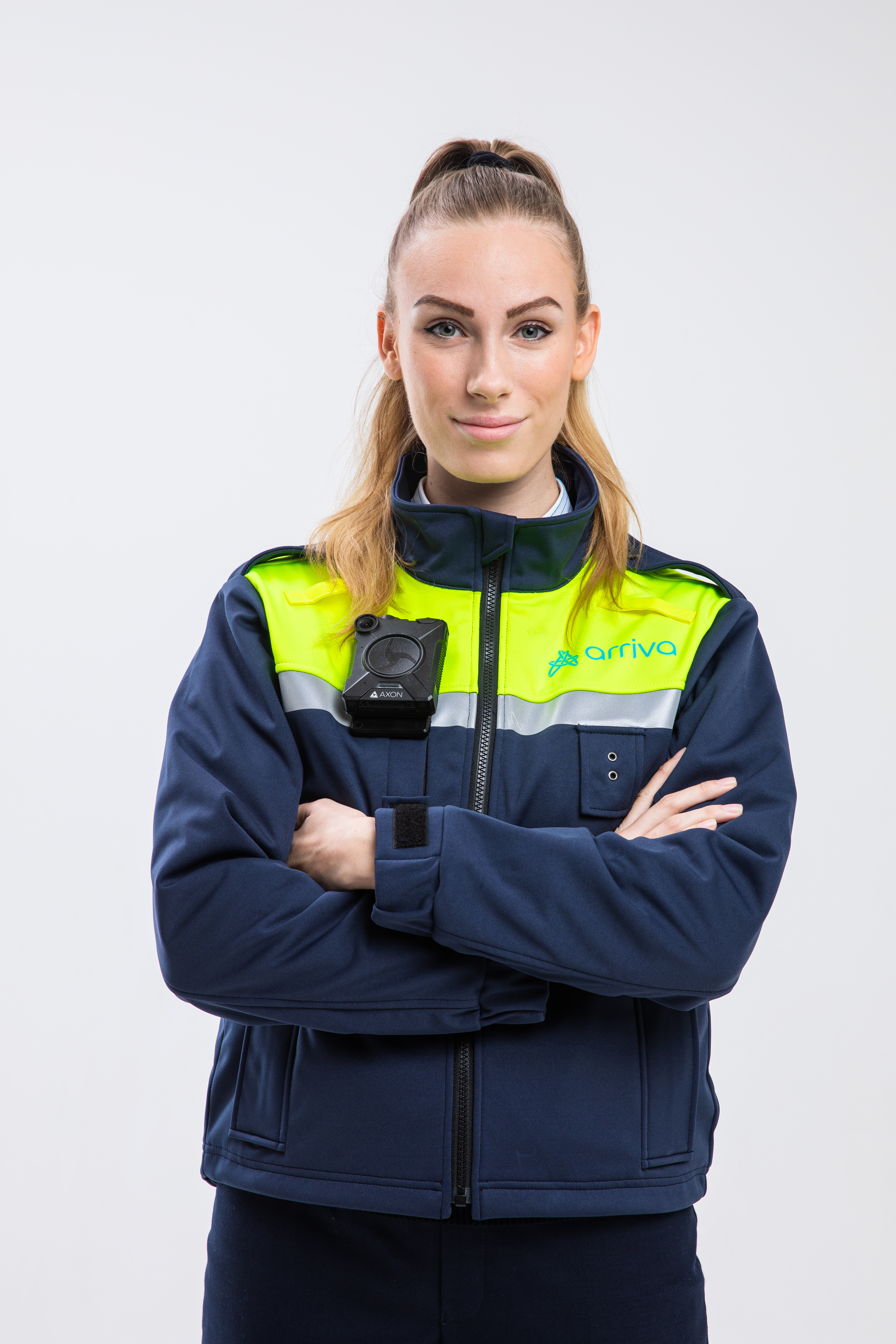 Een jonge vrouwelijke BOA (Buitengewoon Opsporingsambtenaar) kijkt met haar armen over elkaar in de camera, gekleed in een Arriva-uniform.