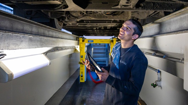 Monteur staat op de brug onder een Arriva-bus met een tablet in zijn hand. Monteur staat op de brug onder een Arriva-bus met een tablet in zijn hand.
