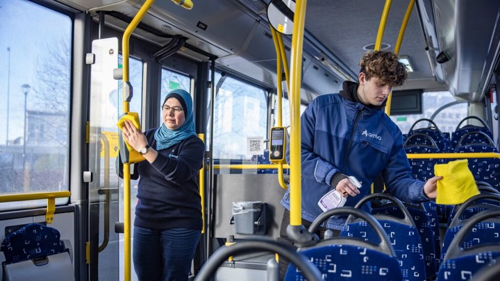 Twee service medewerkers, een jongen en een vrouw, zijn bezig met schoonmaken in een Arriva-bus. Twee service medewerkers, een jongen en een vrouw, zijn bezig met schoonmaken in een Arriva-bus.